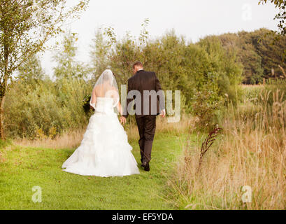 Bride and groom walking alone in nature walk Stock Photo