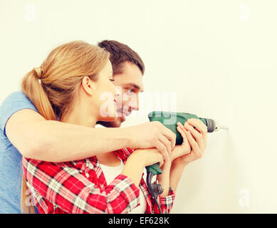 smiling couple drilling hole in wall at home Stock Photo