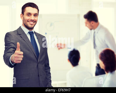 handsome buisnessman showing thumbs up in office Stock Photo