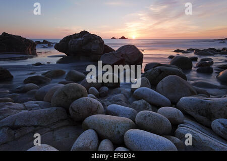 The sun sets over Porth Nanven, also known as the dinosaur egg beach due to the shape of the giant pebbles. Stock Photo