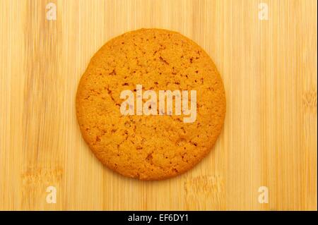 A single ginger nut biscuit on a wooden background Stock Photo
