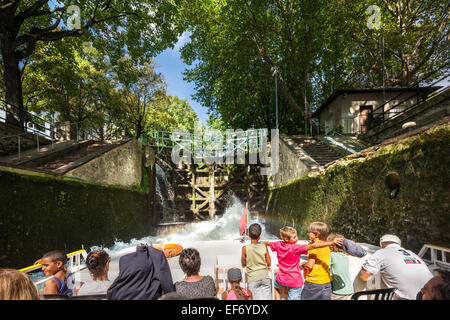 Canal Saint Martin Paris. A tourist canal cruise boat in a lock with family, children watching, enjoying the water gushing in. Stock Photo