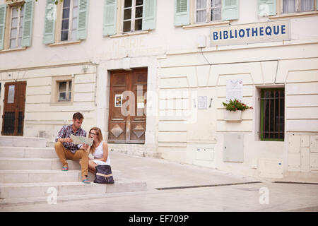 Young Couple on holiday sitting by the town hall in the town of La Colle Sur Loup in the south of France looking at a map Stock Photo