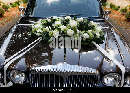 a black wedding car with flower arrangement on the hood Stock Photo