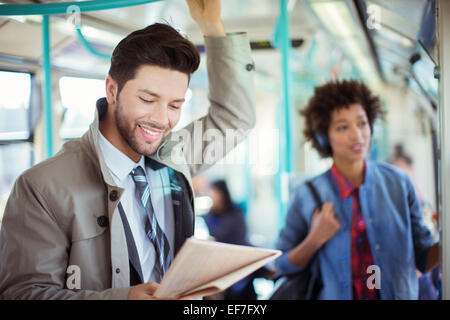 Businessman reading newspaper on train Stock Photo