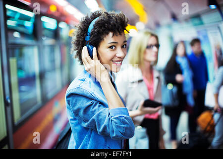 Smiling woman listening to headphones in subway Stock Photo