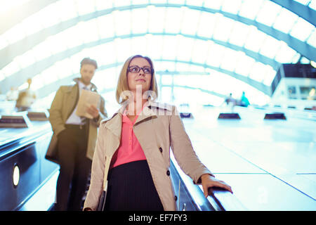 Businesswoman riding escalator Stock Photo