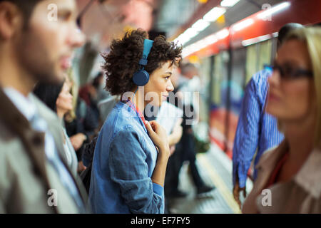 Woman listening to headphones in train station Stock Photo