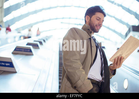 Businessman reading newspaper on escalator Stock Photo