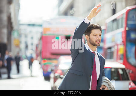 Businessman hailing taxi in city Stock Photo