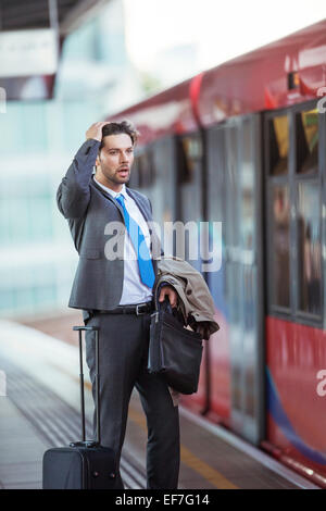 Frustrated businessman missing train in train station Stock Photo