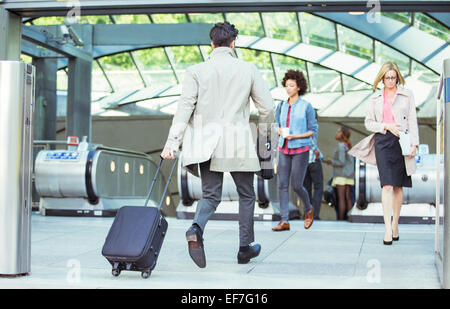 Businessman pulling luggage near escalators Stock Photo