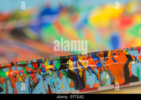 splattered colored paint creating abstract colorful drops of swirling pattern on container Stock Photo