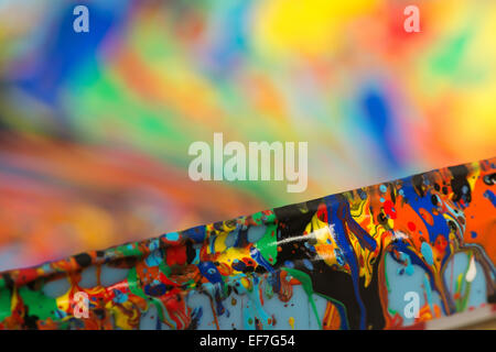 splattered colored paint creating abstract colorful drops of swirling pattern on container Stock Photo