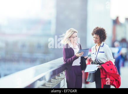 Businesswomen using digital tablet on urban bridge Stock Photo