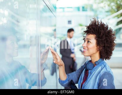 Woman reading transportation schedule at station Stock Photo