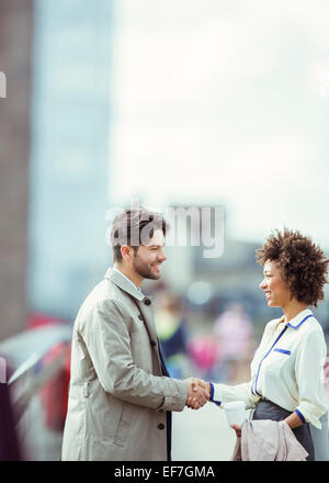 Business people shaking hands outdoors Stock Photo