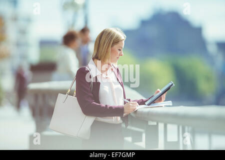 Businesswoman using digital tablet at urban waterfront Stock Photo