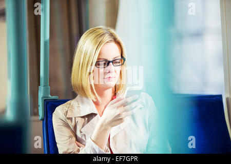 Businesswoman using cell phone on train Stock Photo
