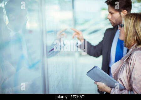 Business people reading transportation schedule at station Stock Photo