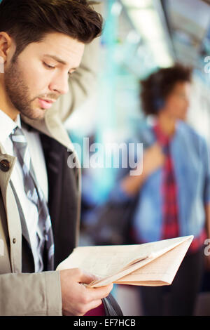 Businessman reading newspaper on train Stock Photo