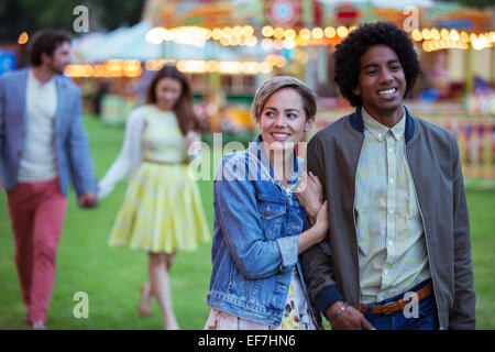 Young multiracial couple smiling while walking in amusement park Stock Photo
