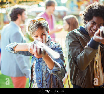 Young couple aiming with guns in amusement park Stock Photo