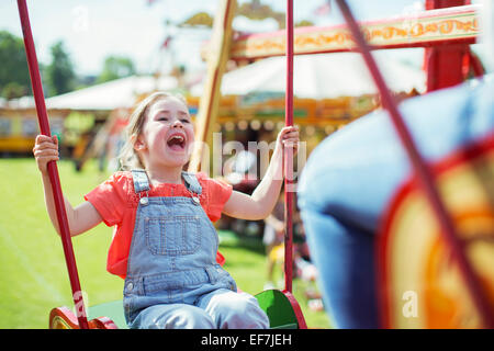 Cheerful girl laughing on carousel in amusement park Stock Photo