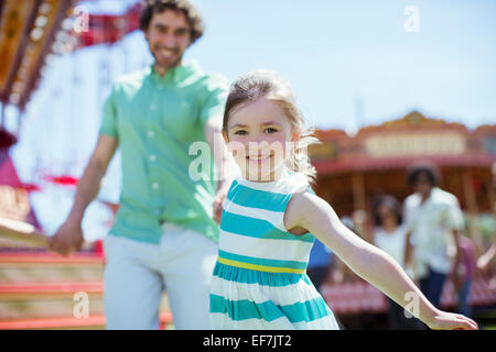 Girl pulling her father in amusement park Stock Photo