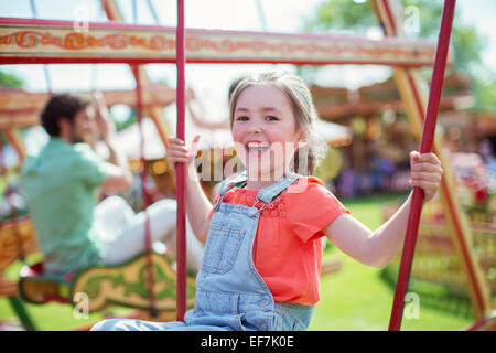 Cheerful girl laughing on carousel in amusement park Stock Photo