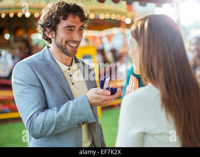 Man proposing to girlfriend in amusement park Stock Photo