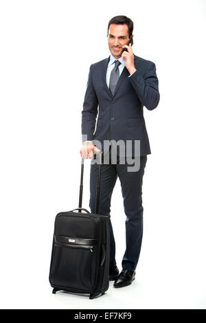 Full length portrait of a smiling businessman with suitcase talking on the phone Stock Photo