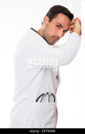 Half length profile portrait of a thoughtful male doctor, looking at camera, his hands leaning to a wall Stock Photo