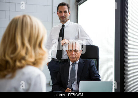 Three businesspeople having a meeting in the office with laptop computer on the desk Stock Photo
