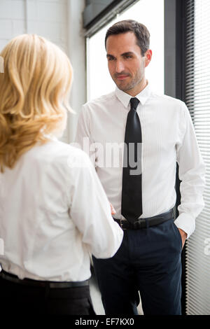 Half length portrait of two businesspeople standing up and shaking hands Stock Photo