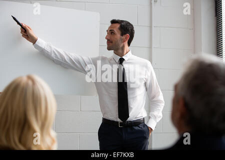 Three businesspeople during a meeting, male manager writing on a blank billboard Stock Photo