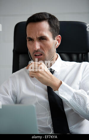 Half length portrait of a angry male businessman with earphones and laptop computer Stock Photo