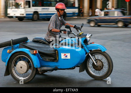 Cuban man riding vintage motorbike with sidecar, Havana, Cuba Stock Photo