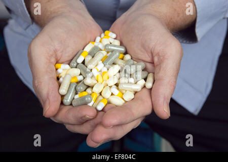 A man's two hands are cupped together holding a variety of medicines, pills and capsules. Stock Photo