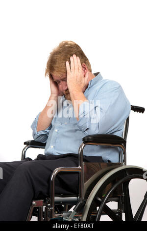 Elderly paraplegic in wheelchair holds his head in his hands as he suffers from depression because of a medical problem. Stock Photo
