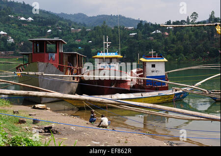 Metal cargo boats and wooden fishing boats on the Rwandan site of Lake Kivu. Rwanda Stock Photo