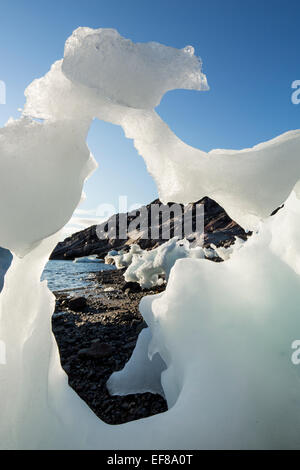 Canada, Nunavut Territory, Setting midnight sun lights melting iceberg stranded at low tide in Frozen Channel at northern edge o Stock Photo