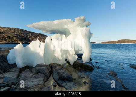 Canada, Nunavut Territory, Setting midnight sun lights melting iceberg stranded at low tide in Frozen Channel at northern edge o Stock Photo