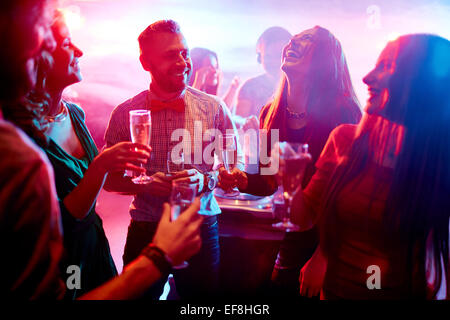 Ecstatic friends with champagne talking at party in night club Stock Photo