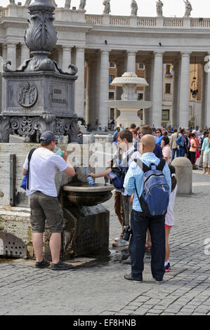 A young man filling a plastic bottle with water from a water fountain in St Peter's Square, Vatican City, Rome, Italy. Stock Photo