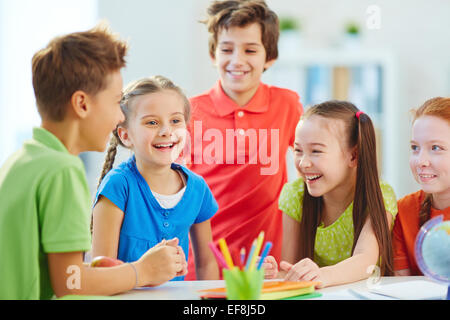 Friendly boys and girls talking and laughing at break in school Stock Photo