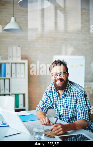 Bearded businessman in casualwear sitting at workplace Stock Photo