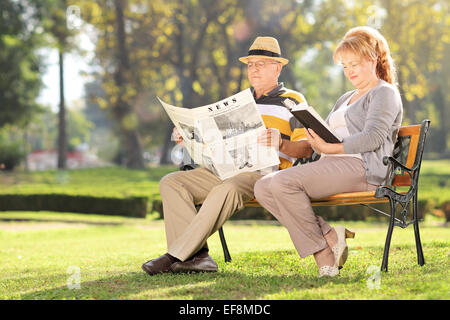 Mature couple relaxing seated on a bench in park Stock Photo