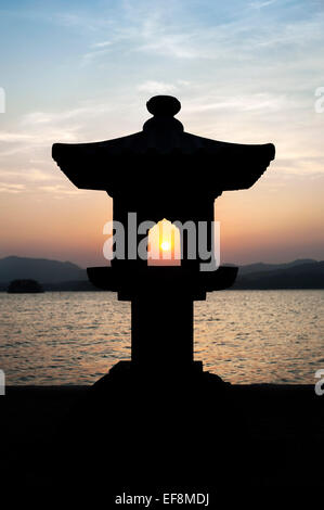 Sunset caught through a silhouetted lantern on West Lake, China Stock Photo