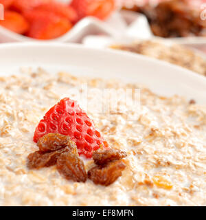 closeup of a bowl with porridge with sultana raisins and strawberry Stock Photo